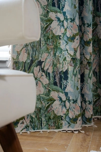 Close-up of green floral jacquard fabric with elegant fringe tassels on the edge