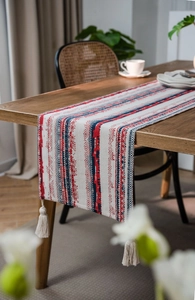 Detailed close-up of tribal style table runner with striped patterns and white tassels