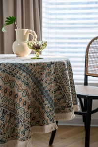Close-up of thick geometric woven round tablecloth featuring bohemian fringe details