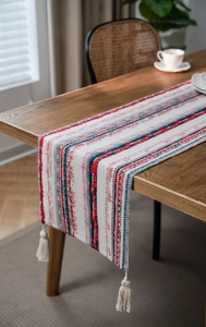 Detail of bohemian table runner with blue geometric patterns and white tassels