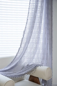 Detail of lavender crochet lace curtain with geometric patterns and tassel fringes