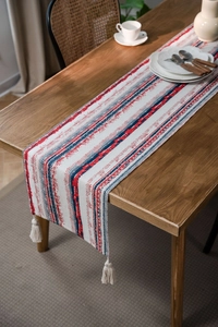 Close-up of red and navy striped table runner with geometric textures and fringe tassels