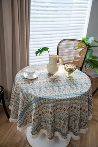 Close-up of geometric jacquard pattern and delicate cream tassels on a round tablecloth