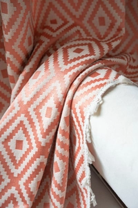 Detailed macro view of woven bohemian throw blanket with orange geometric diamond patterns