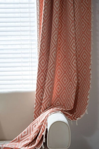 Close-up of bohemian coral orange geometric pattern fabric with creamy tassel details