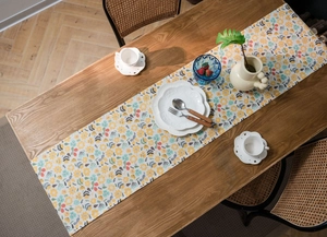 Detail of floral table runner with tassels on wood table for a cozy dining atmosphere