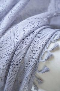 Close-up detail of grey crochet hollow lace fabric with elegant tassel trim