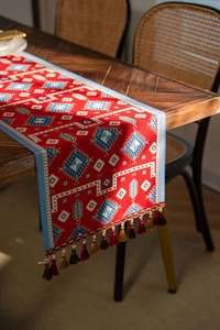 Close-up of red festive table runner with blue geometric patterns and tassel detail