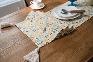 Floral table runner with fringe on dark wood table, cozy home dining room setting