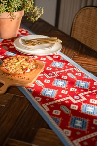 Close-up of red jacquard table runner with blue geometric diamond patterns and piping