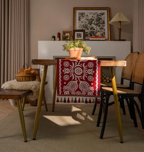 Detailed embroidery on vintage red table runner with colorful fringe and floral patterns