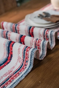 Detail of bohemian geometric table runner with tassels on a rustic wooden table