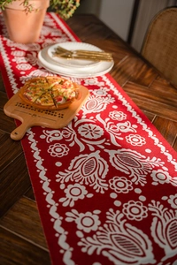 Close-up of red and white jacquard table runner with folk floral patterns on wood table