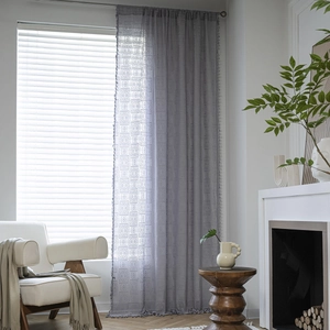 Grey crochet lace curtain with geometric embroidery and fringe tassels in living room