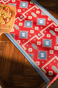 Macro detail of red ethnic jacquard runner with blue geometric patterns and woven edges