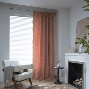 Brick red geometric diamond pattern curtain with white tassels in a cozy home setting