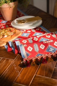 Detail of red jacquard table runner with geometric patterns and fringe edges
