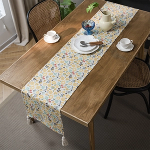 Floral print table runner with tassels on a wooden dining table for home decor