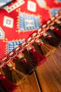 Macro shot of red jacquard table runner with bohemian geometric motifs and tassel details