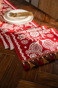 Detailed view of red jacquard table runner with floral patterns and woven fringe tassels