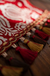 Detailed close-up of red jacquard table runner with intricate floral patterns and silk tassels