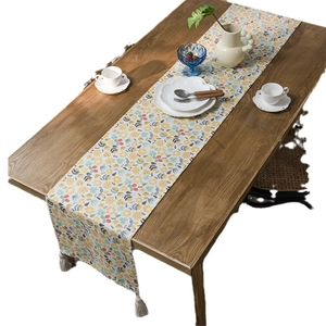 Floral print table runner with elegant tassels on a dark wooden dining table
