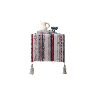 Bohemian table runner with red and blue geometric patterns and fringed tassels on white background