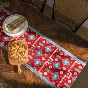 Ethnic red table runner with geometric patterns and blue borders on wooden table