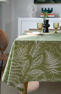Detail of green tablecloth with white leaf patterns on a wooden dining table