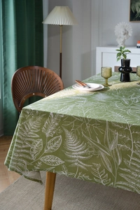 Detail of green tablecloth with white fern leaf patterns and premium cotton linen texture