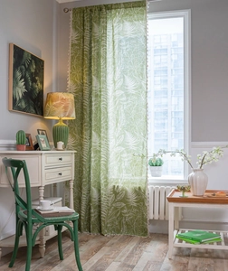 Detail of sage green curtains with white leaf patterns and delicate tassel trim decor