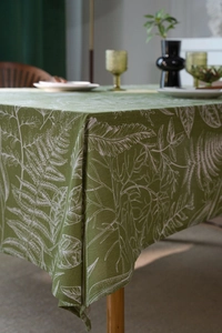 Detail of green leaf print tablecloth showing fabric texture and neat edge stitching