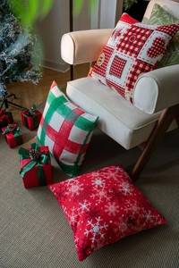Detail of festive Christmas pillow covers with red plaid and snowflake patterns for sofa decor