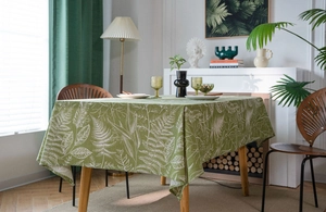 Close-up detail of green rectangular tablecloth featuring white tropical leaf prints and texture