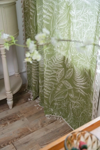 Detail showing green botanical leaf pattern fabric with elegant white tassel fringes