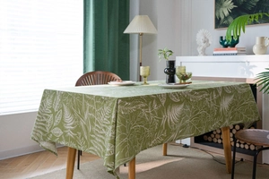 Detailed view of olive green tablecloth with white fern leaf patterns in home setting