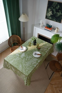 Detailed top view of a green tablecloth with white leaf patterns in a cozy dining setting