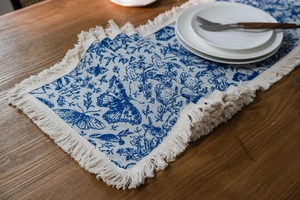 Dettaglio del runner da tavola con farfalle blu e nappe su un tavolo di legno caldo
