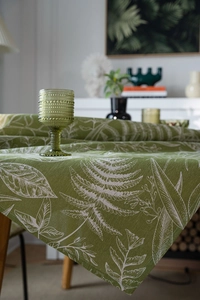 Detailed macro view of green tablecloth with white fern leaf patterns and linen texture