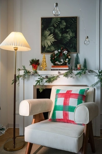 Detail of red and green plaid Christmas pillow cover on a cozy white armchair