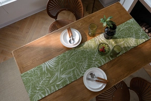 Dettaglio di runner da tavola verde con motivi di felce su mobile in legno scuro