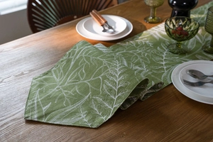 Vista dettagliata del runner da tavola con motivo a foglie su legno e accessori pranzo