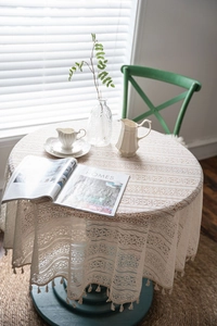 Detail of cream crochet lace tablecloth with floral patterns and handmade tassel edges