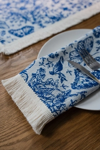 Dettaglio del runner da tavola toile de jouy blu e bianco con nappine decorative crema