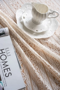 Detail of beige lace tablecloth showing intricate crochet hollow knitting and floral texture