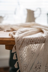 Close-up of white crochet lace tablecloth featuring floral hollow patterns and tassel edges