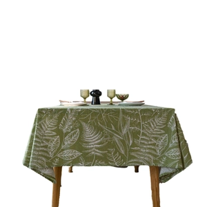 Green tablecloth with white leaf sketches on wood table, rectangle linen fabric cover