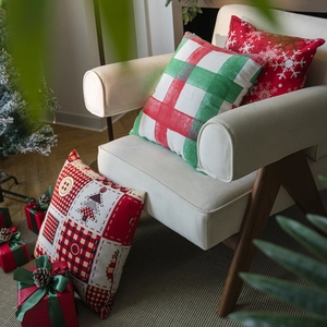 Festive Christmas pillow covers with red and green plaid and snowflake prints on a chair