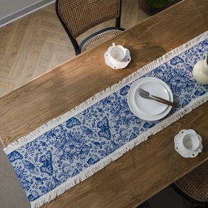 Runner da tavola con farfalle blu, decorazioni floreali e nappe su tavolo di legno