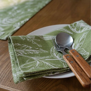 Runner da tavola verde con foglie tropicali in cotone e lino su legno scuro